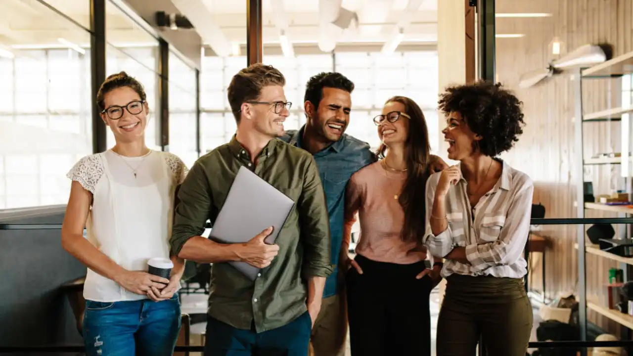 Smiling employees in a positive work environment, a result of streamlined HR processes through outsourcing.