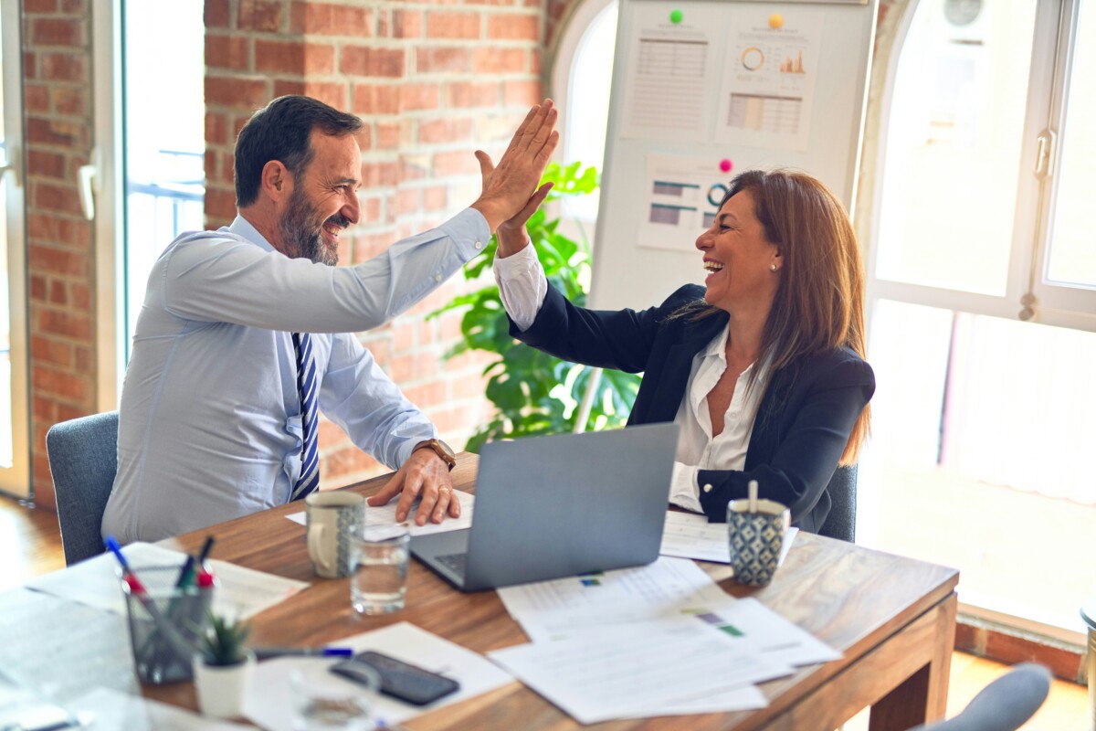 two people high five each other in office