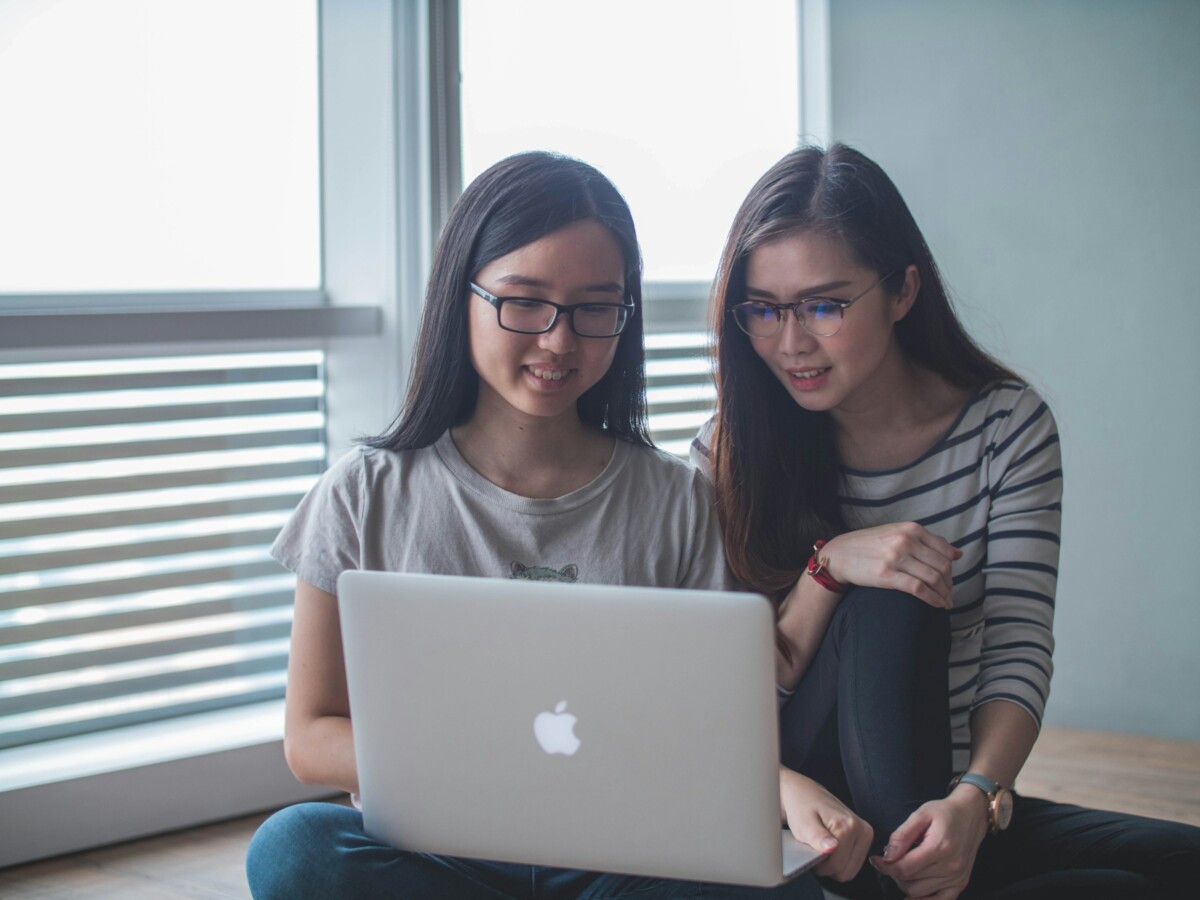 two women looking at laptop and smile