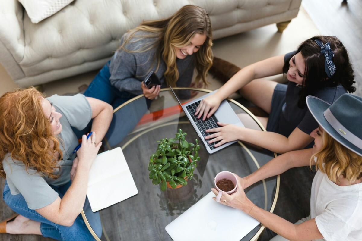 women sitting, laughing and typing on laptop