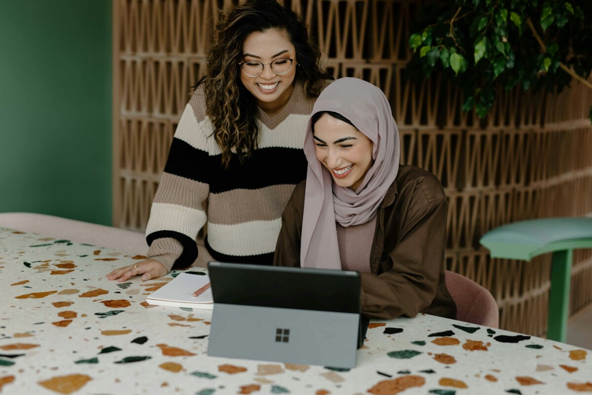 two woman looking at laptop and smiling