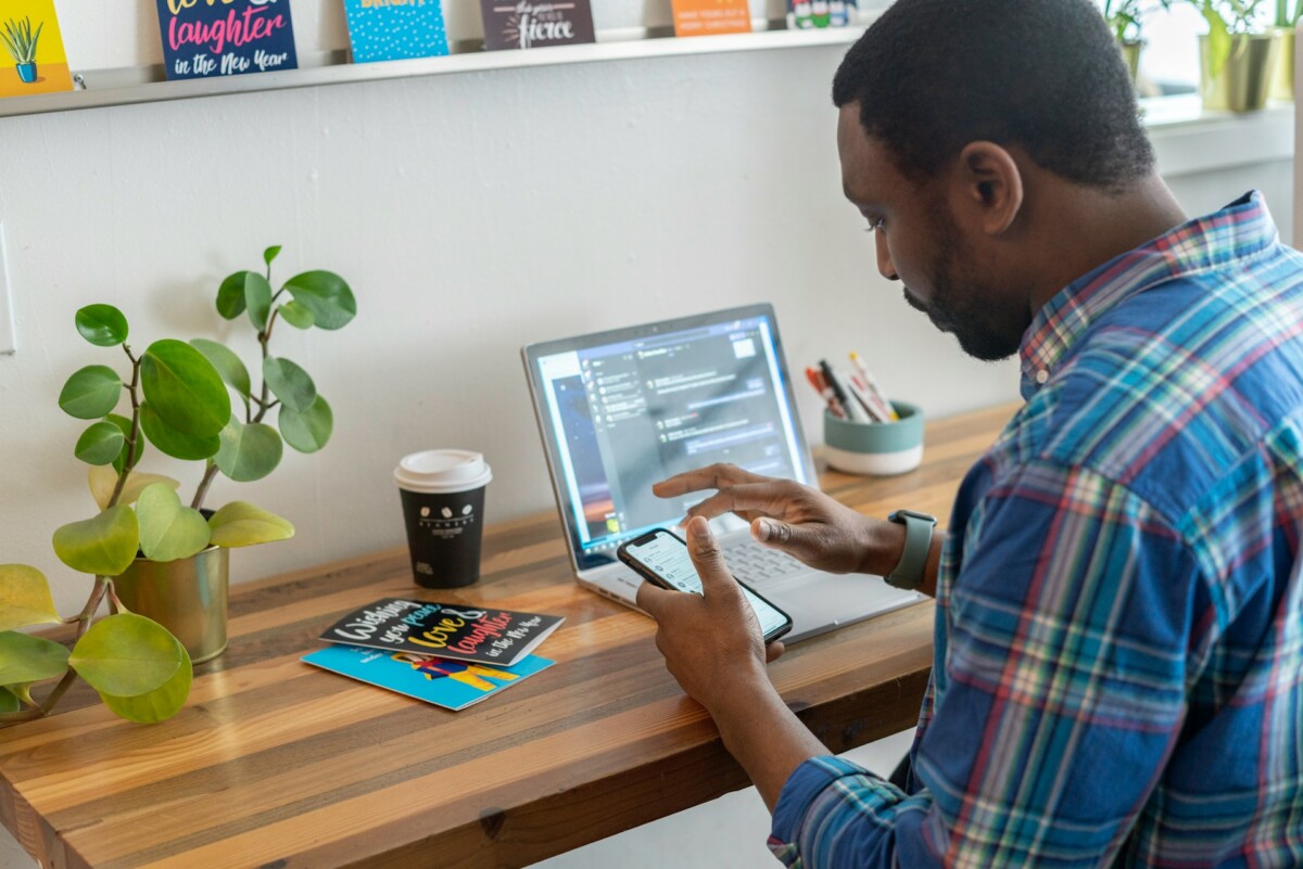 Man in front of laptop holding his phone
