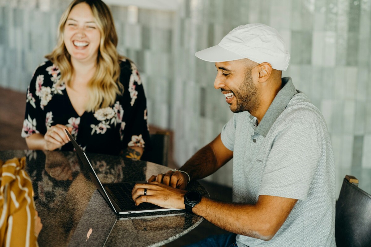 Two people, in front of laptop laughing