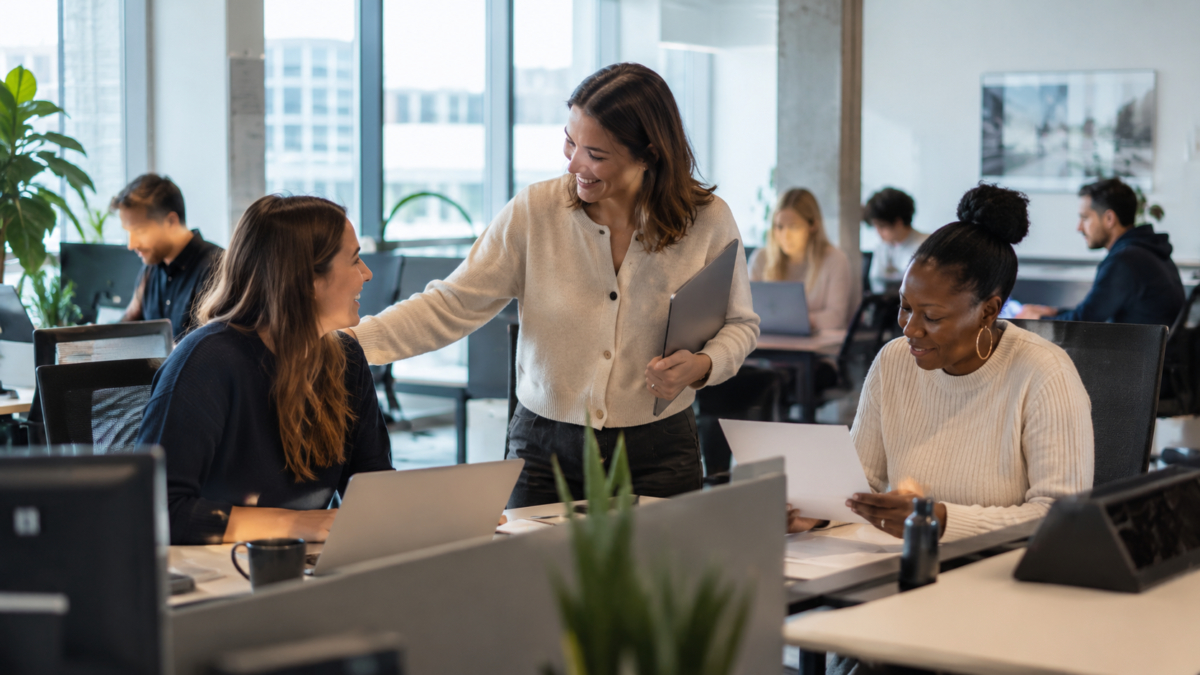 New European tech employee being welcomed in a live office while HR and finance complete onboarding and payroll checks